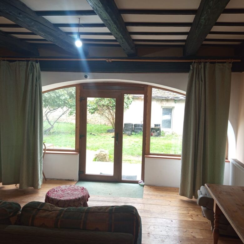 Charming living room featuring large windows overlooking a lush garden, perfect for relaxing and enj.