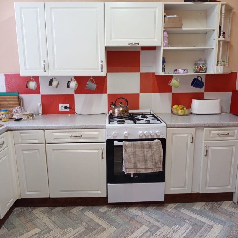 Spacious kitchen with white cabinets, red backsplash, and modern appliances in Vulcan Brasov.