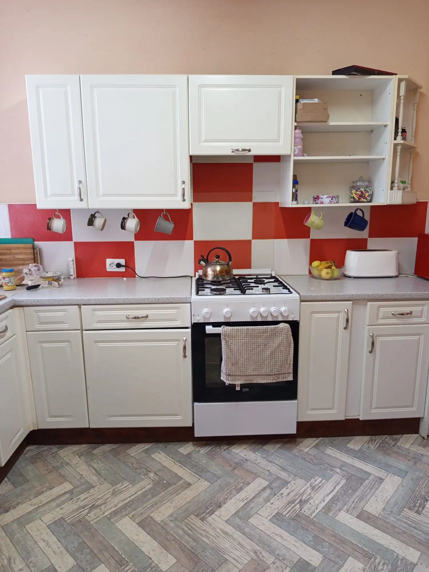 Spacious kitchen with white cabinets, red backsplash, and modern appliances in Vulcan Brasov.