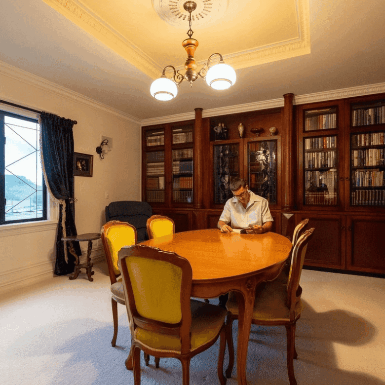 Elegant interior of a luxury château featuring a wooden bookshelf-lined wall and a classic dining ta.