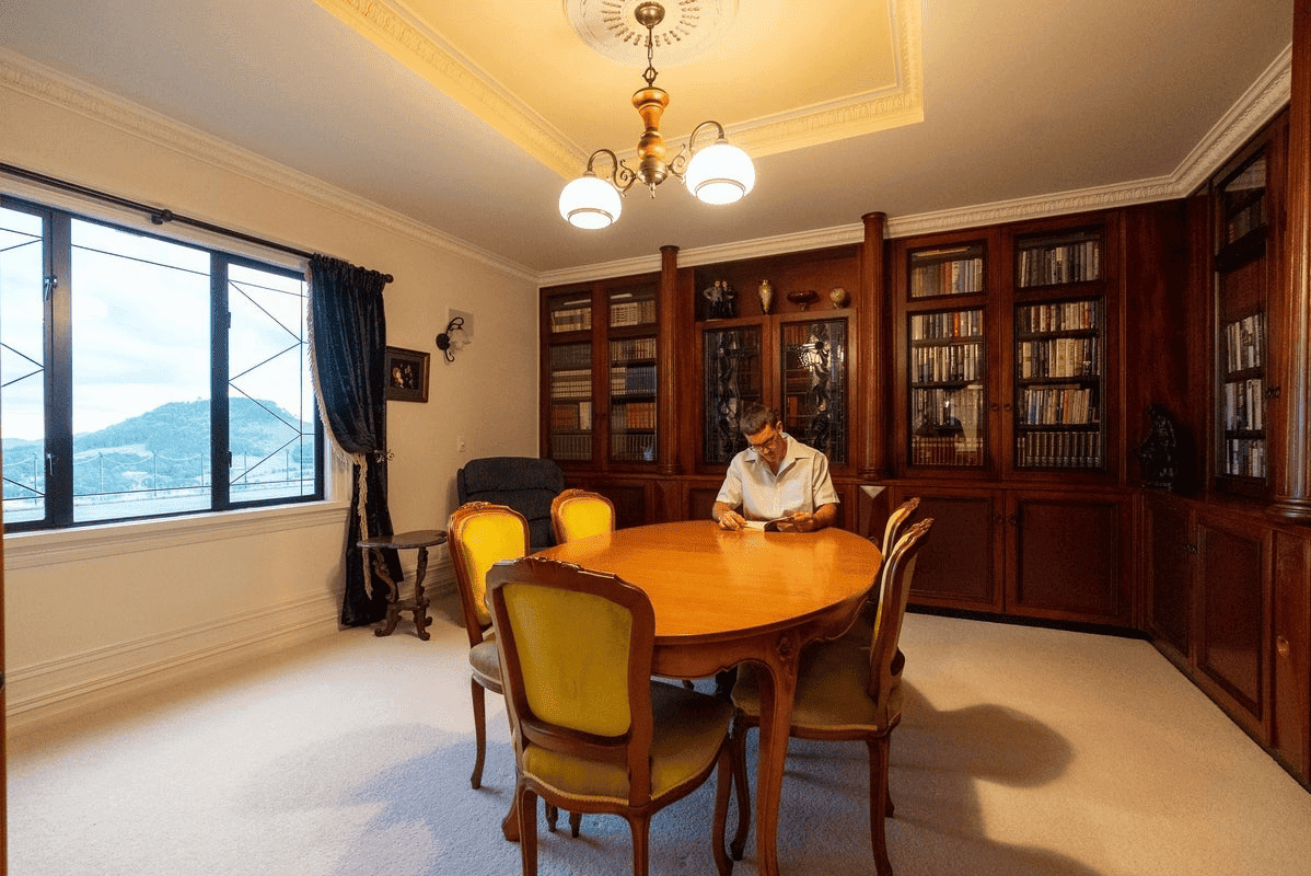 Elegant interior of a luxury château featuring a wooden bookshelf-lined wall and a classic dining ta.