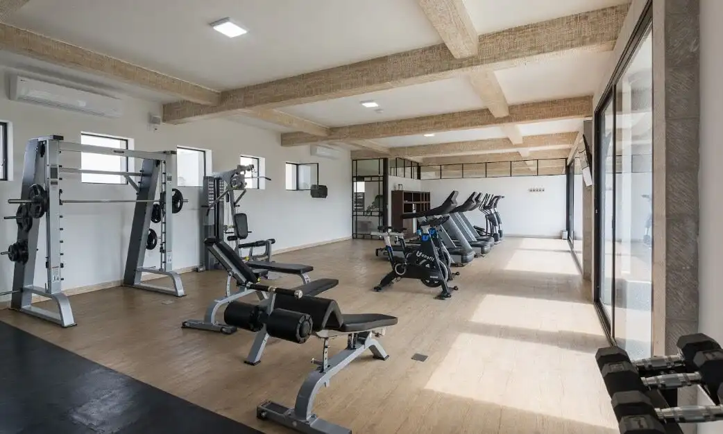 Equipped fitness room featuring modern exercise machines and ample sunlight.