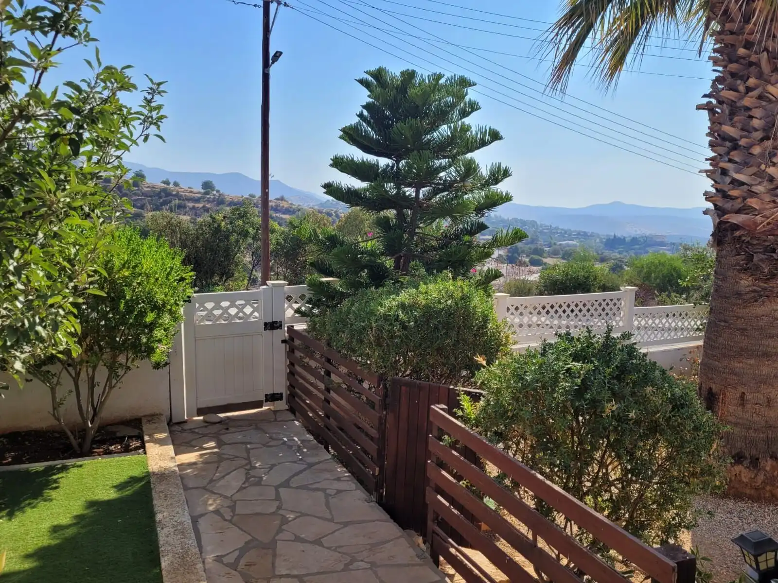 Beautiful garden with lush plants, trees, and mountain scenery in the background.