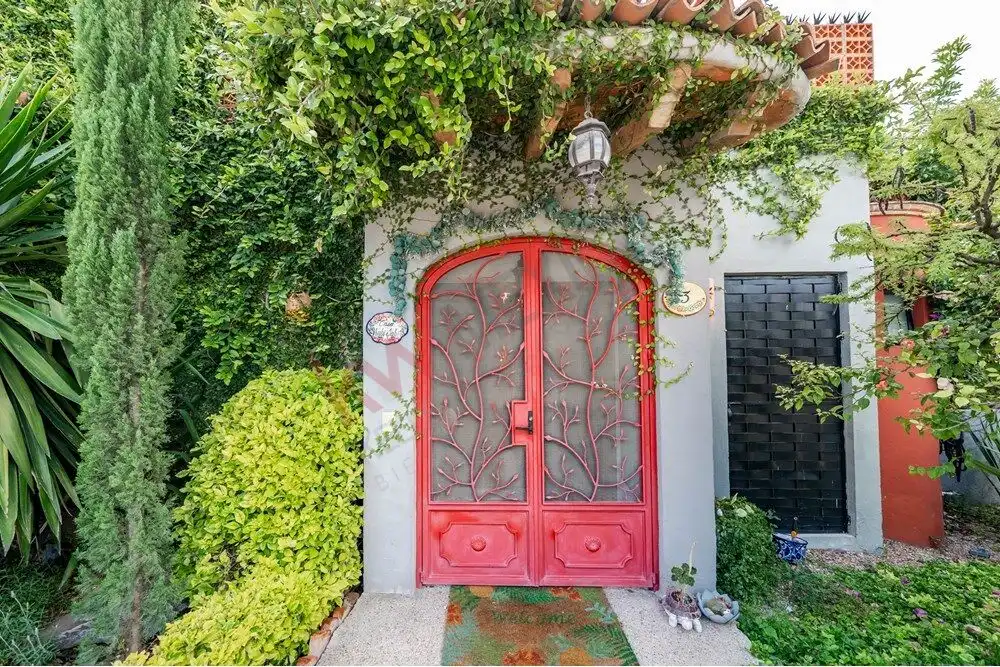 Entrance door with intricate ironwork in a lush garden setting.
