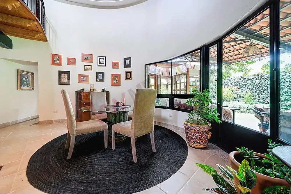 Style dining room with a round table and plush chairs. Bright, airy space with large windows and vib.