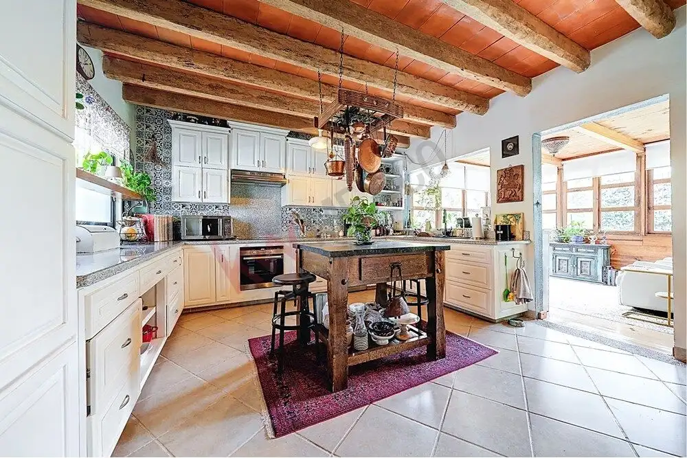 Cozy kitchen with rustic wooden beams, white cabinetry, and modern appliances in a beautiful colonia.
