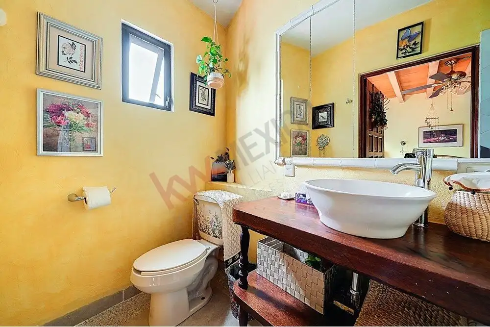 Bright bathroom with yellow walls, modern sink, and decorative artwork.