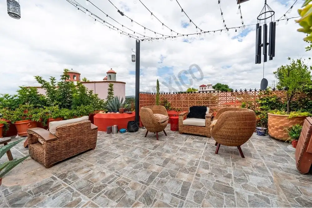 Outdoor patio with wicker furniture and string lights in a colonial-style home.