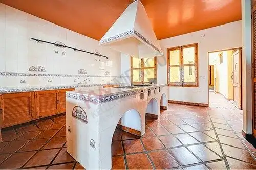 Charming Spanish colonial kitchen featuring terracotta tiles, wooden cabinets, and large windows for.