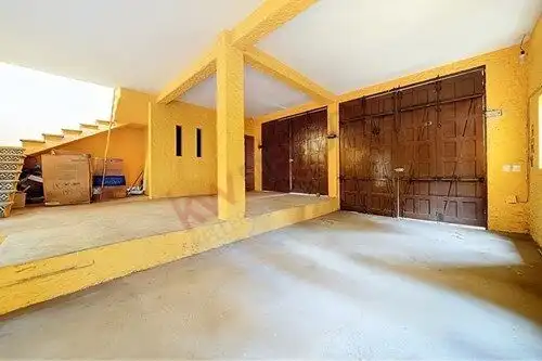 Spacious garage with wooden doors and yellow walls in a luxurious estate in San Miguel de Allende.