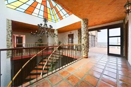 Elegant interior with terracotta tiles, chandelier, and stained glass skylight in a Spanish colonial.