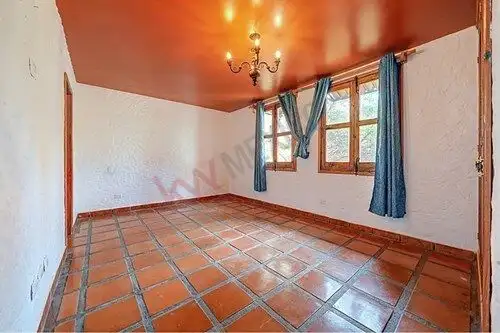 Spacious room with terracotta tiled floors and large windows in a Spanish colonial estate.