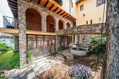 Spanish colonial estate with stone arches and lush garden in San Miguel de Allende.