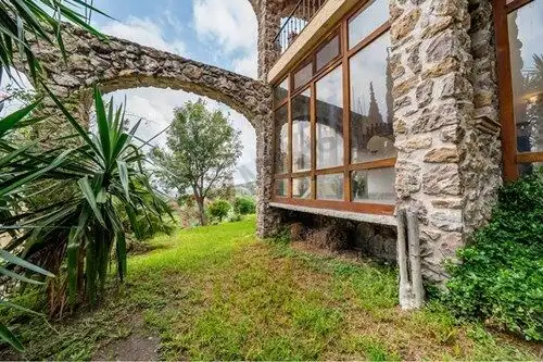 Spanish Colonial estate with stone and glass architecture, lush garden, and panoramic views in San M.