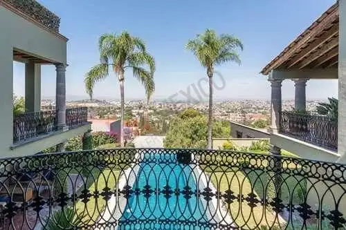 Elegant estate balcony overlooking lush gardens and scenic cityscape in San Miguel de Allende.