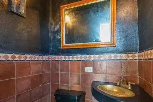 Spanish Colonial style bathroom with terracotta tiles and a gold sink.
