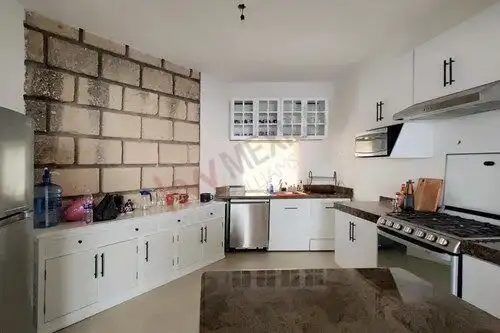 Spacious kitchen featuring white cabinetry, stainless steel appliances, and a brick accent wall.