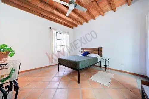 Bright bedroom in San Miguel de Allende with wooden ceiling and terracotta tiles.