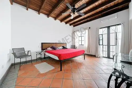 San Miguel de Allende luxury bedroom with high wooden ceiling and large windows for natural light.