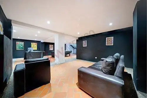 Stylish living room featuring black leather sofas, vibrant wall art, and warm terracotta flooring in.