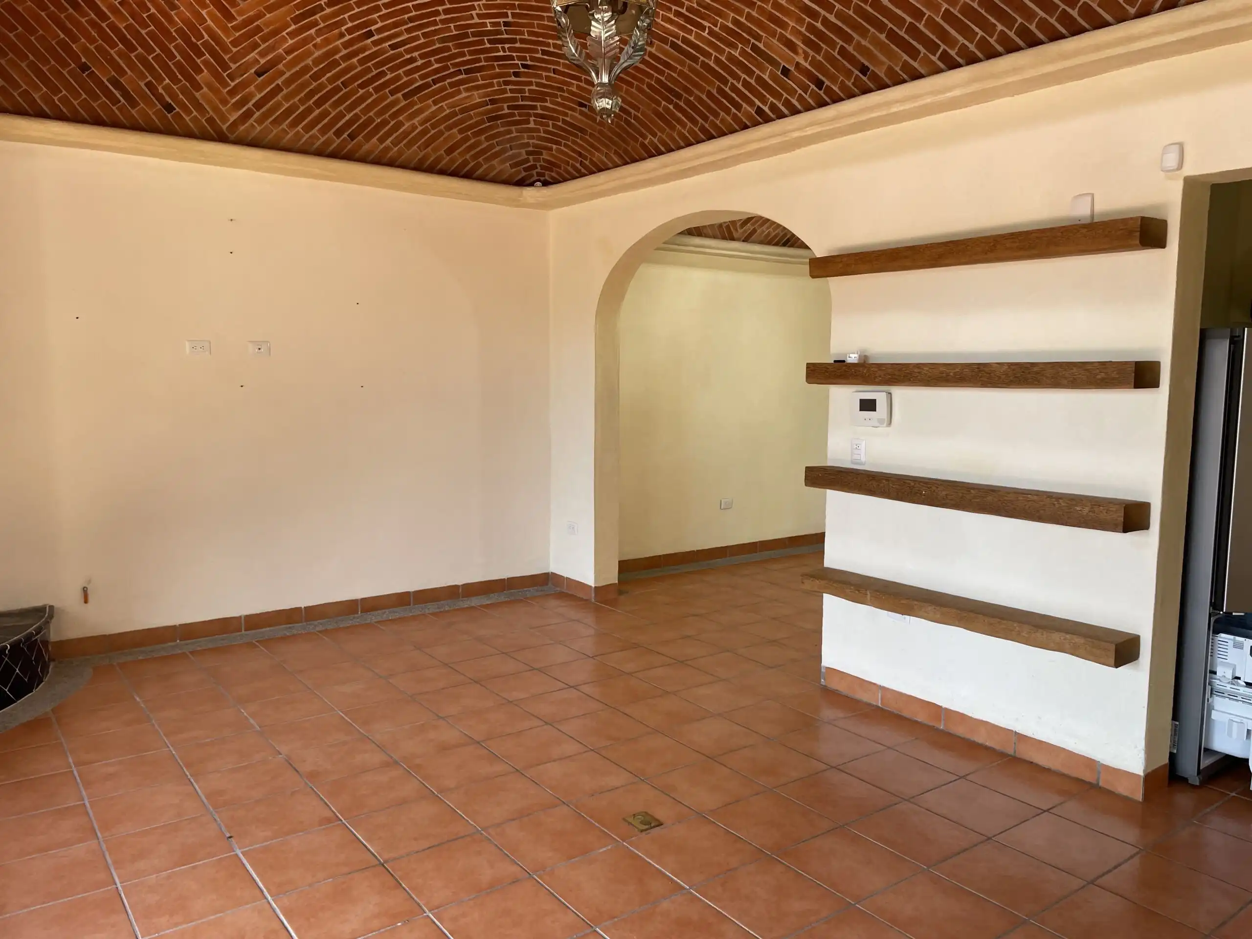 Level home interior with warm terracotta tiles and wooden shelves in Rancho Los Labradores.