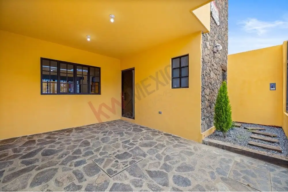 Bright yellow exterior with stone accents and a cozy patio.
