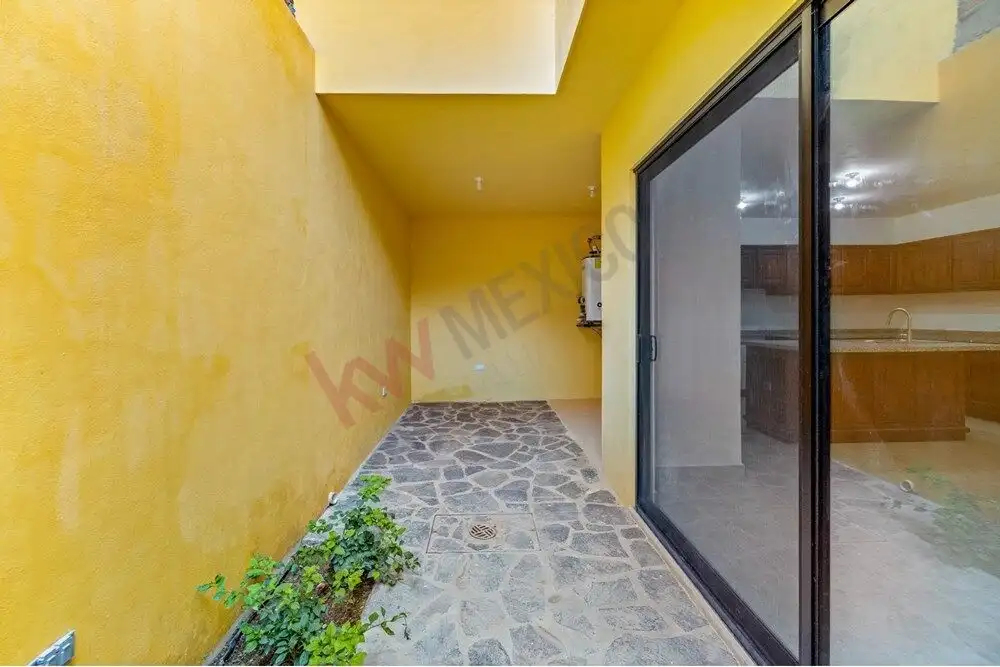 Bright yellow exterior wall with stone pathway and large glass sliding door.