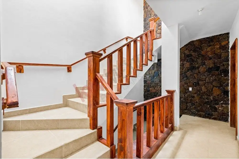 Staircase with wooden handrails and beige tiles in a modern San Miguel de Allende home.
