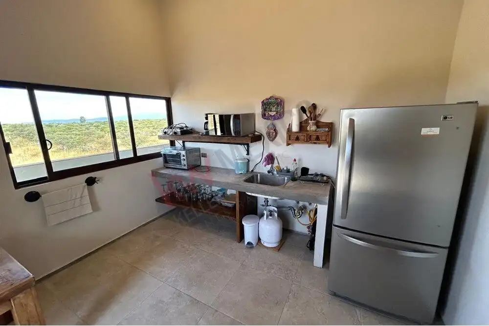 Modern kitchen with large window overlooking nature Bright kitchen featuring a large window with scenic views and essential appliances.