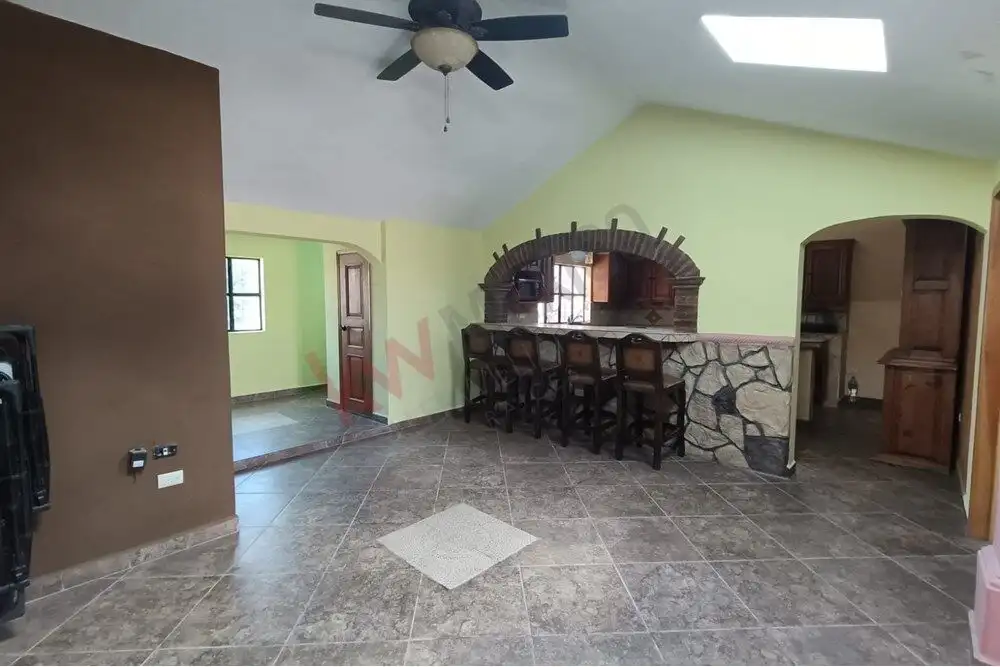 Cozy living area with rustic brick fireplace, bar seating, and open kitchen in a countryside retreat.