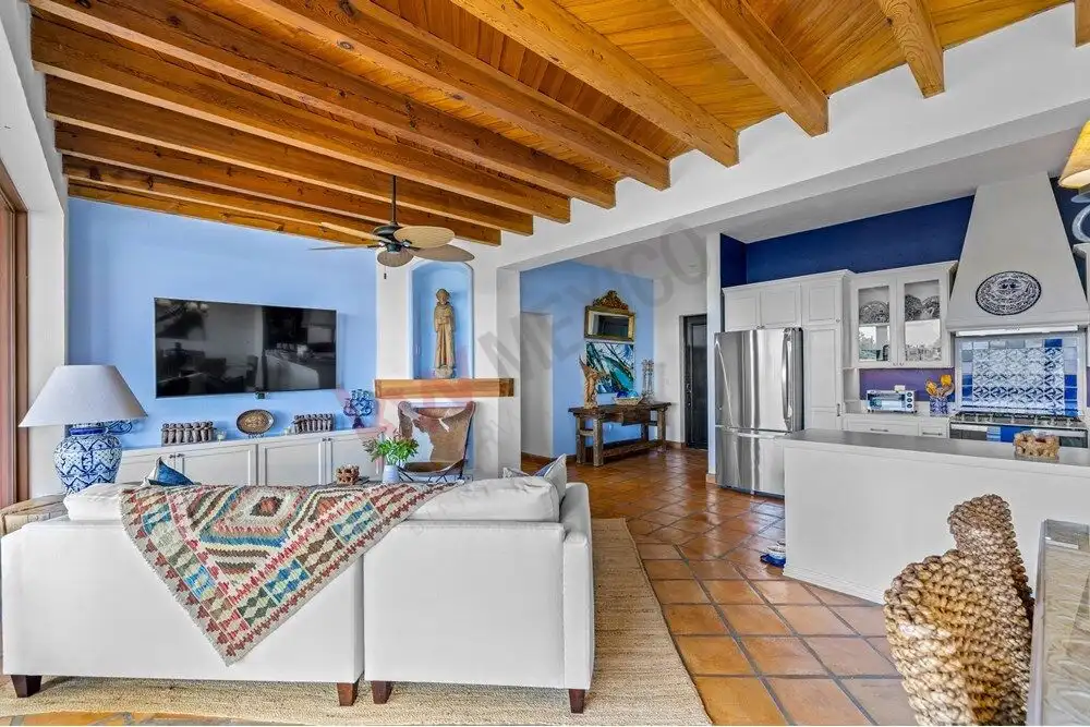 Bright living room with blue accent walls and wooden ceiling beams, featuring modern decor and spaci.