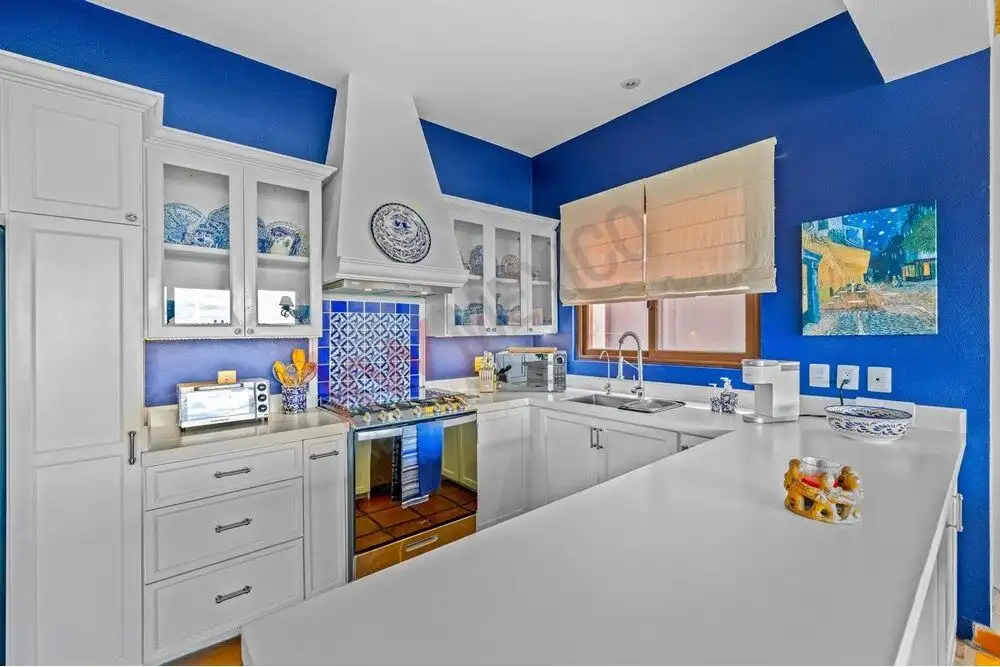 Bright kitchen with white cabinets and blue walls in Capilla de Piedra.
