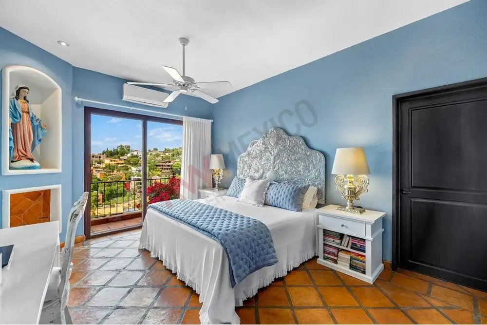 Cozy bedroom with blue walls, elegant headboard, and natural light in Capilla de Piedra.