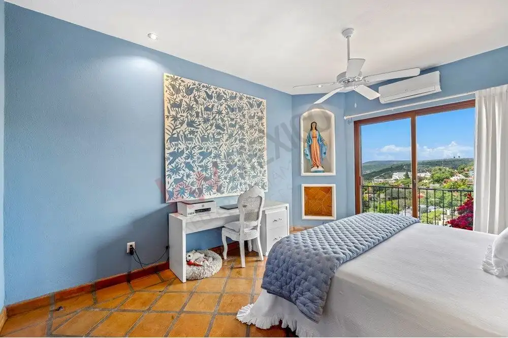 Level bedroom with blue walls, artwork, and a balcony view in Capilla de Piedra.