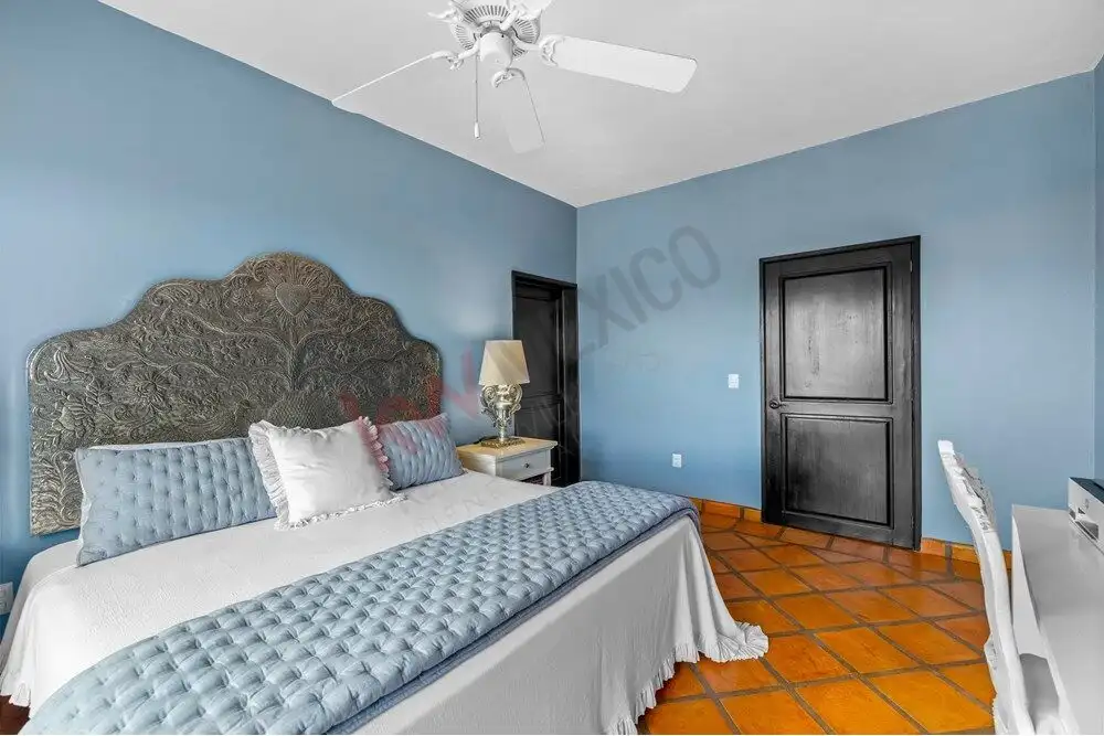 Bright bedroom with blue walls, elegant headboard, and modern decor in San Miguel de Allende.