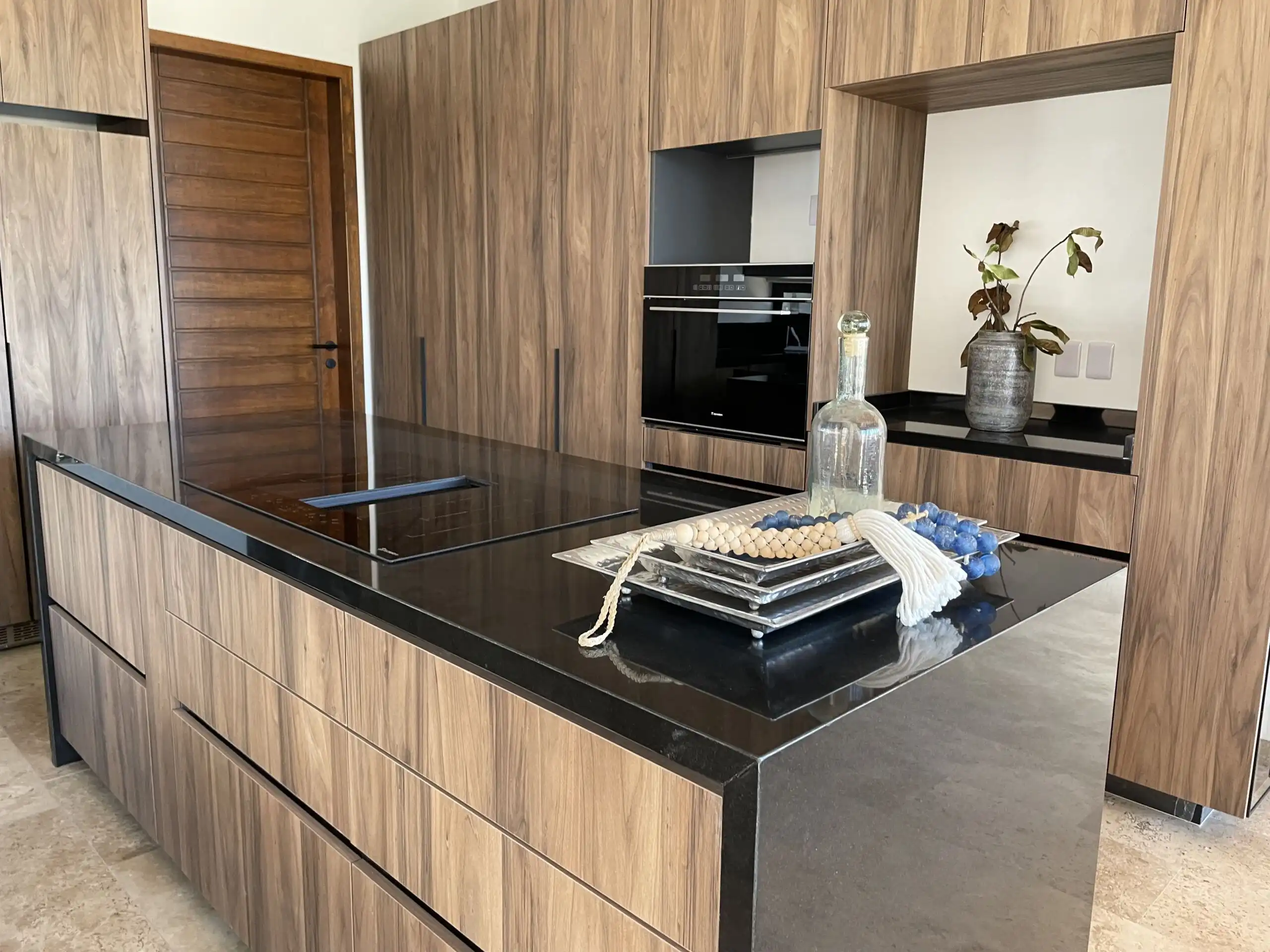 Modern kitchen with wooden cabinetry and black countertops.
