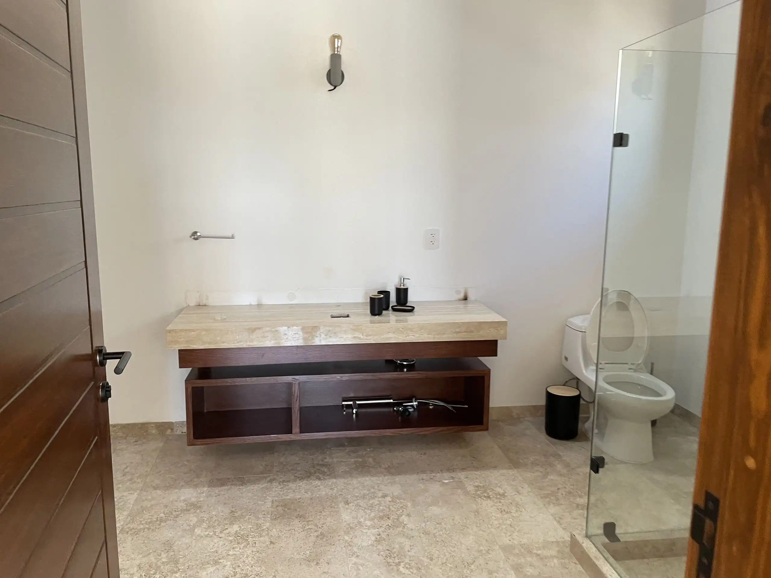 Modern bathroom with minimalist design, featuring a marble vanity and glass-enclosed shower.