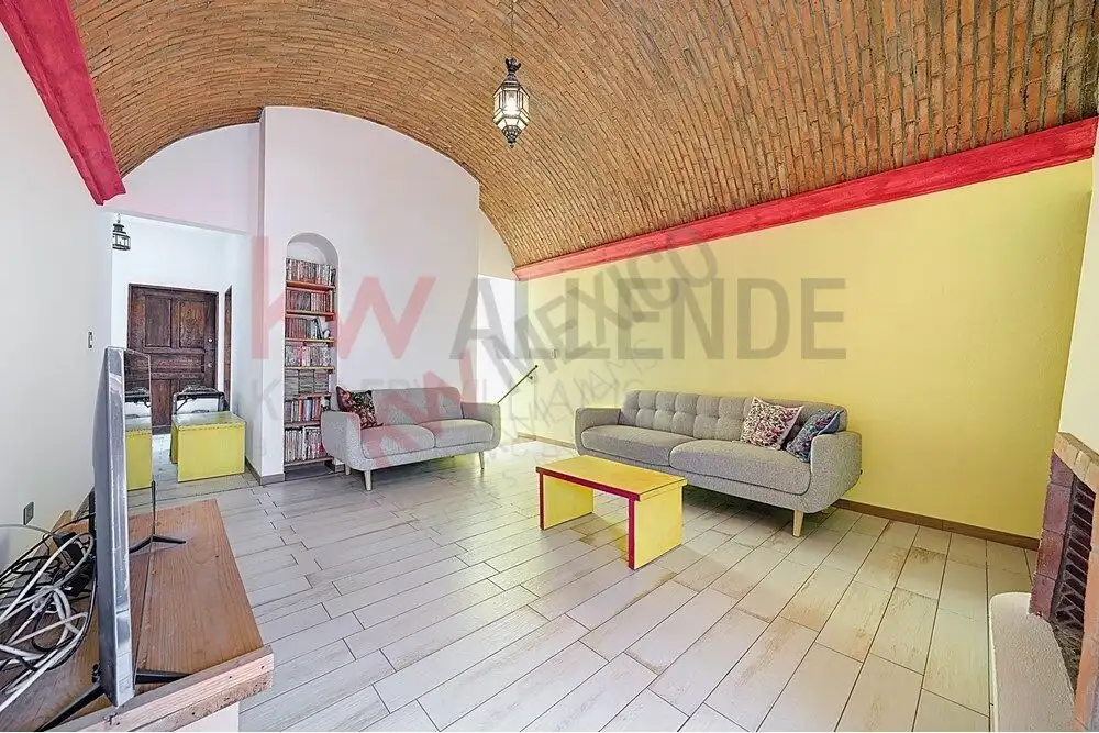 Style Living Room in San Miguel de Allende Spacious living room with vaulted brick ceiling, bright yellow walls, and comfortable sofas in a bea.