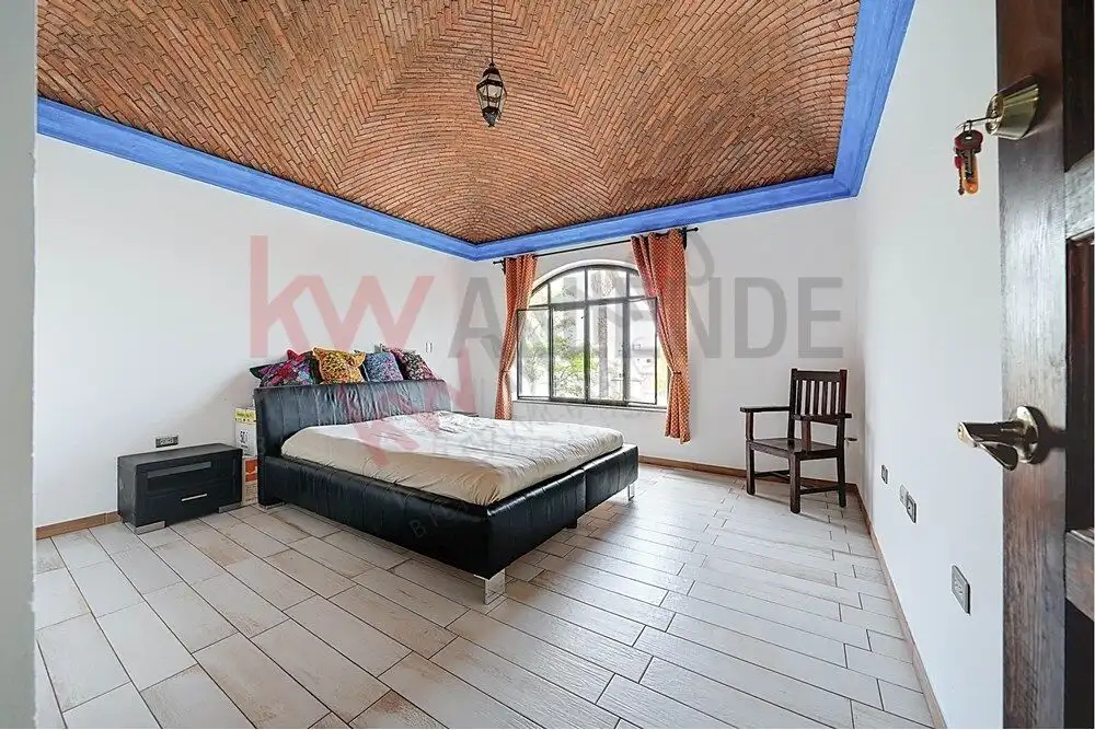 Elegant bedroom with vaulted brick ceiling in San Miguel de Allende. Spacious bedroom featuring a vaulted brick ceiling, large window, and simple decor.