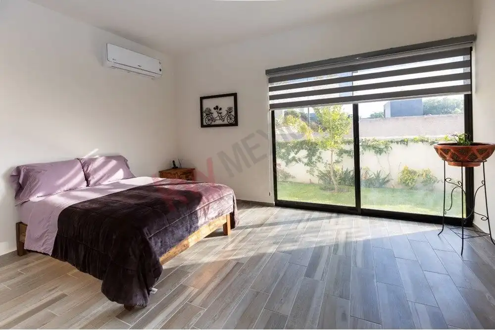 Spacious bedroom featuring a large window overlooking a lush garden, perfect for relaxing and enjoyi.