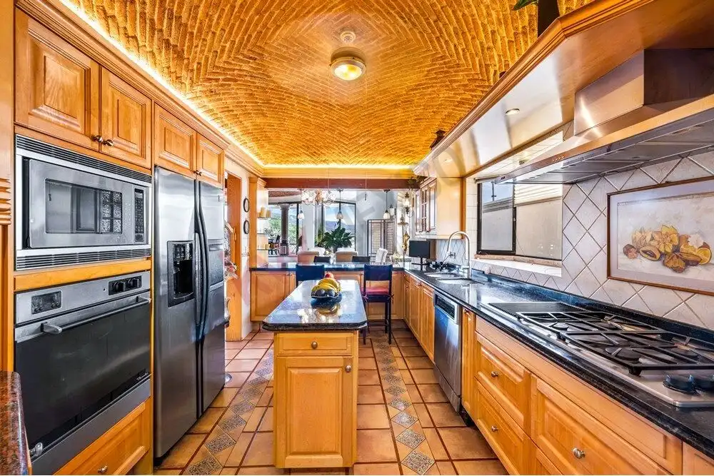 Spacious kitchen featuring wooden cabinets, stainless steel appliances, and large windows with sceni.