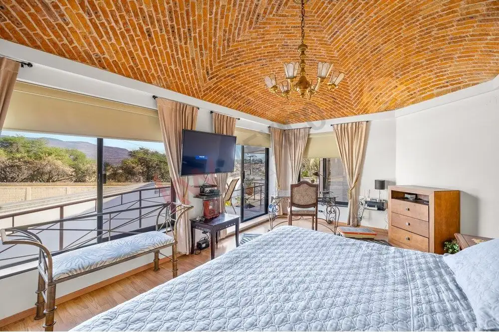 Elegant bedroom featuring large windows and scenic landscape views in a colonial-style home.