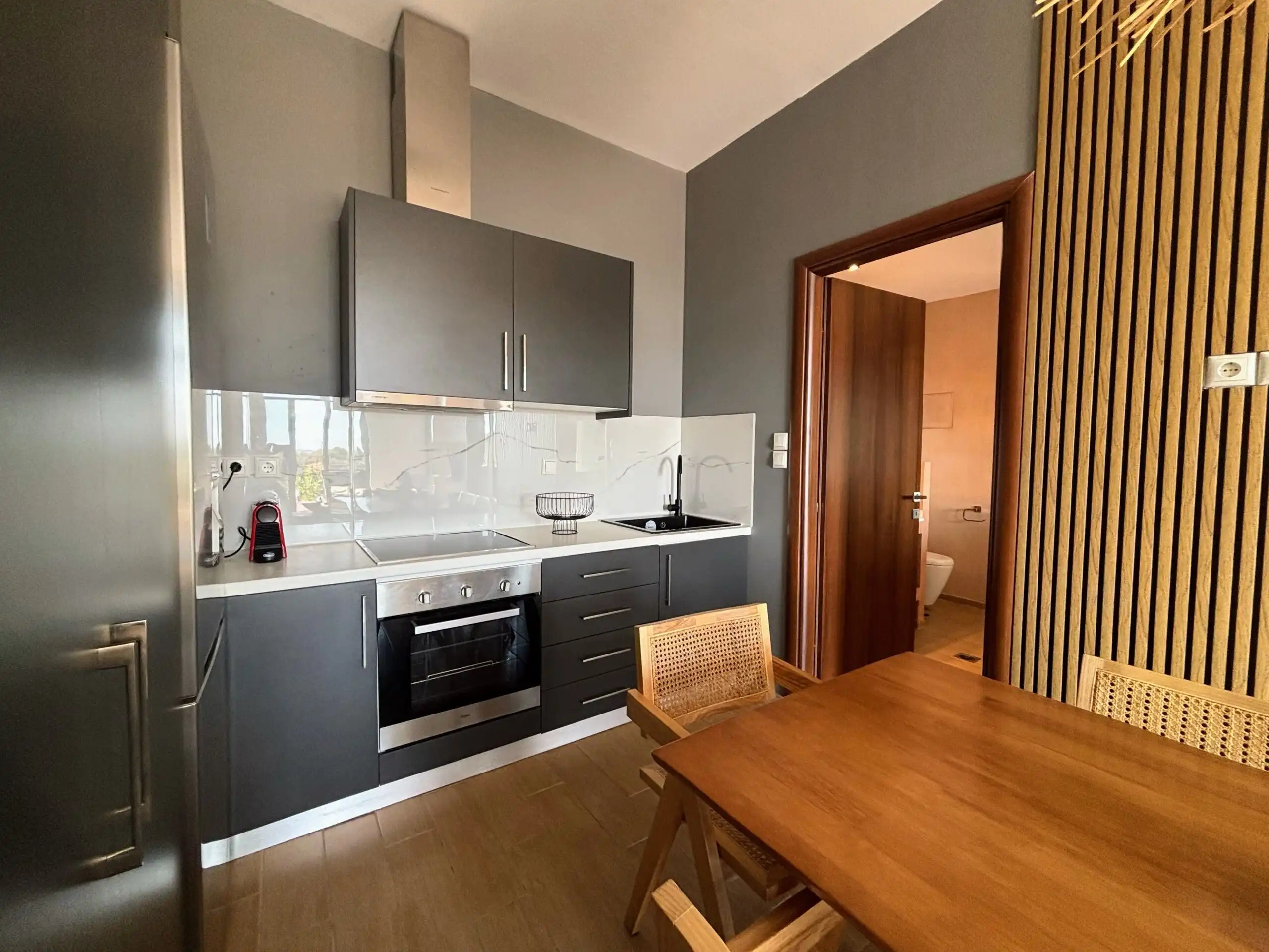 Luxury villa kitchen with gray cabinetry and wooden dining table in Skiathos, Greece.