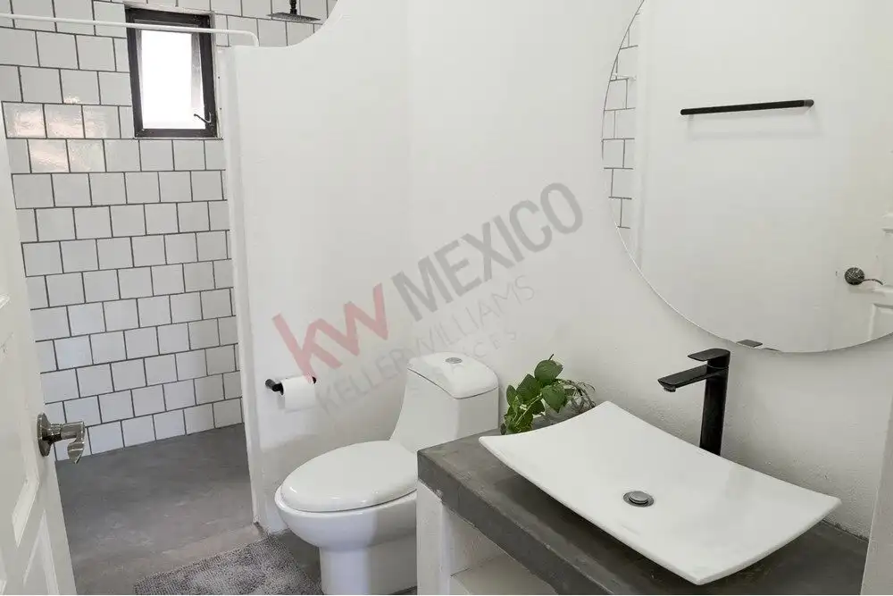 Modern bathroom with white tiles and minimalist design Bathroom with white tiles, modern fixtures, and a sleek sink in a contemporary home.