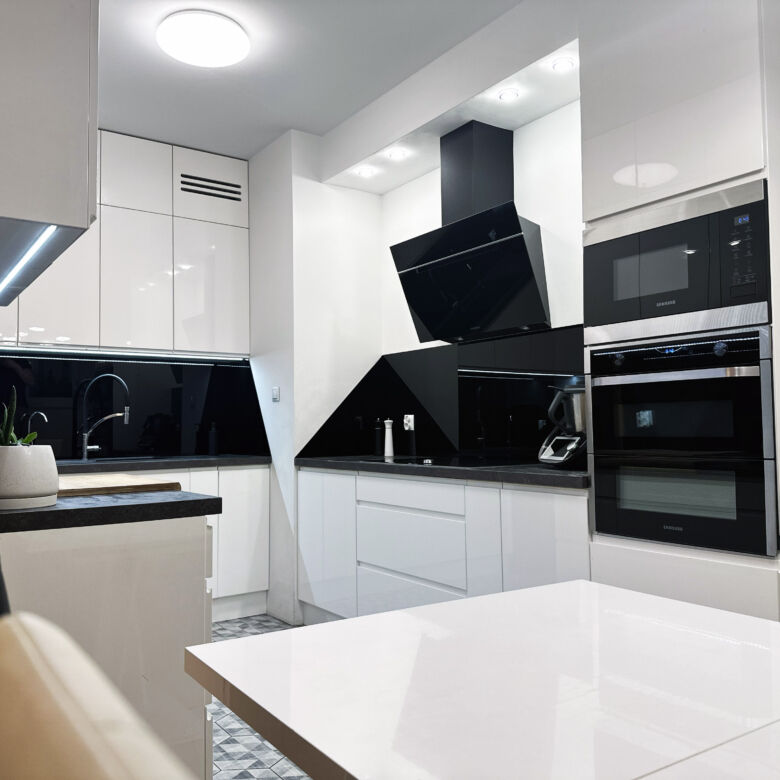 Modern kitchen with sleek black and white design in Warsaw apartment.
