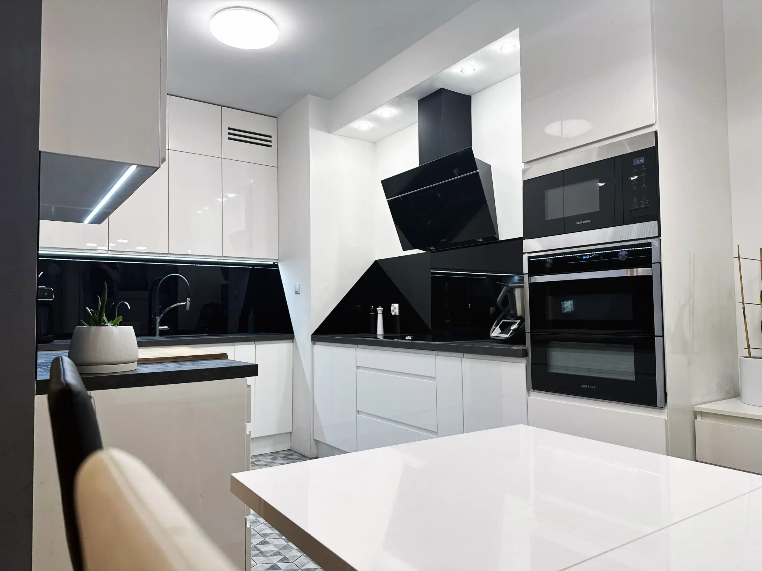 Modern kitchen with sleek black and white design in Warsaw apartment.