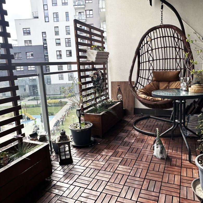 Modern Warsaw apartment balcony with cozy hanging chair and potted plants.