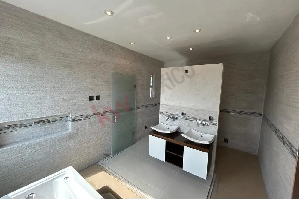 Spacious bathroom featuring dual sinks, modern fixtures, and sleek tile decor.