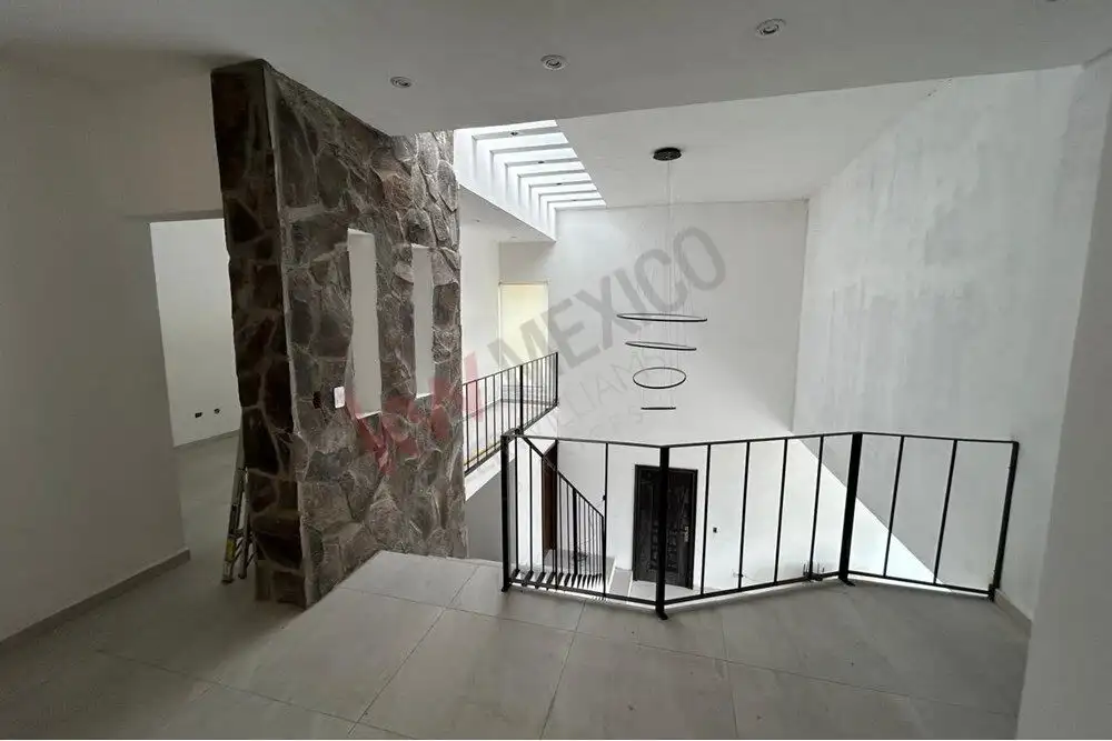 Staircase with black metal railing inside a stylish, bright home.