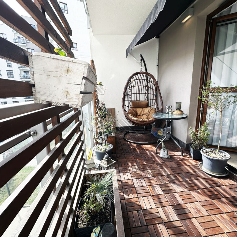 Balcony of a modern 2-bedroom apartment in Warsaw with outdoor seating and potted plants.